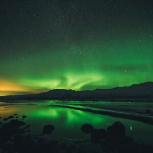 Colorful orange and green Northern Lights being reflected on the water surface in Thórsmörk, Iceland. Original public domain image from Wikimedia Commons